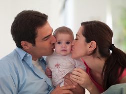 Mother and father kissing baby daughter