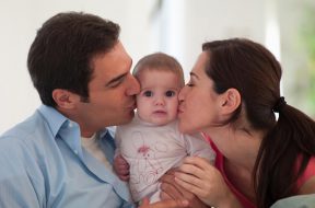 Mother and father kissing baby daughter