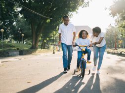 man-standing-beside-his-wife-teaching-their-child-how-to-1128318