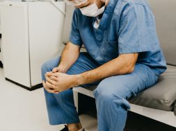 man-wearing-blue-scrub-suit-and-mask-sitting-on-bench-3279197