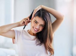 Portrait of a beautiful young woman brushing her hair in the bathroom at home