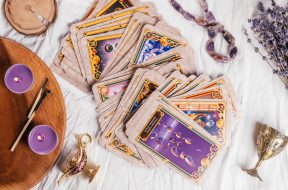 Tarot cards spread face up on white cloth sheet with wooden tray, lavender, candles and attributes. Top view. Minsk, Belarus, 27.09.2021