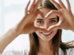 Healthy Eyes And Vision. Portrait Of Beautiful Happy Woman Holding Heart Shaped Hands Near Eyes. Closeup Of Smiling Girl With Healthy Skin Showing Love Sign. Eyecare. High Resolution Image