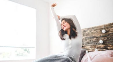 Cropped shot of a young woman stretching while sitting in her bed