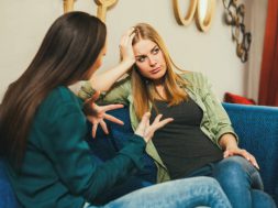 Young woman is sad, she is talking to a friend in cafe.