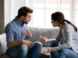 Stressed young married family couple arguing emotionally, blaming lecturing each other, sitting on couch. Depressed husband quarreling with wife, having serious relations communication problems.