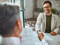 Happy male candidate greeting a member of human resource team on a job interview in the office.