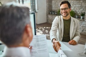 Happy male candidate greeting a member of human resource team on a job interview in the office.